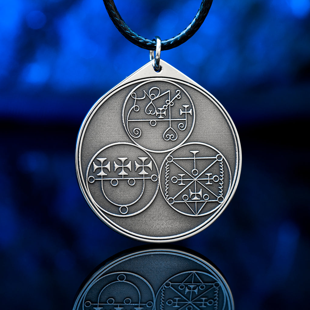 Reverse side of the Feline Goetic Trinity pendant with three engraved demon sigils of Sitri, Ose and Beleth from the Ars Goetia. Silver-tone Goetic talisman necklace on a black cord against a blue background.