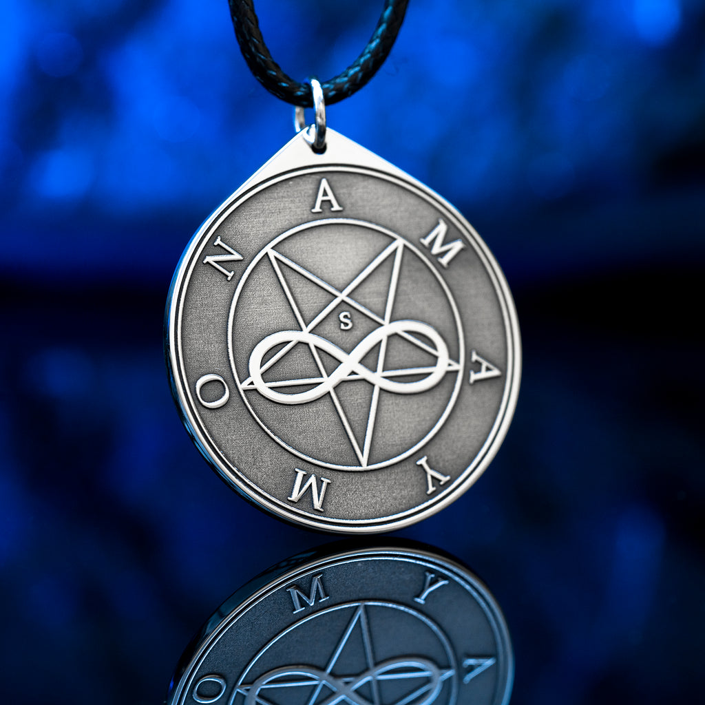 Amaymon Seal Pendant featuring an engraved inverted pentagram, intertwined infinity symbol and Amaymon lettering. Round silver tone occult medallion on a black braided cord, photographed against a deep blue background with a reflection