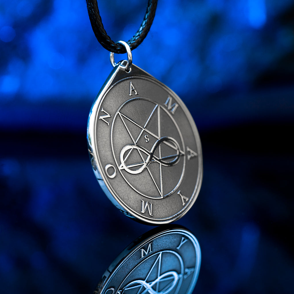 Amaymon Seal Pendant featuring an engraved inverted pentagram, intertwined infinity symbol and Amaymon lettering. Round silver tone occult medallion on a black braided cord, photographed against a deep blue background with a reflection